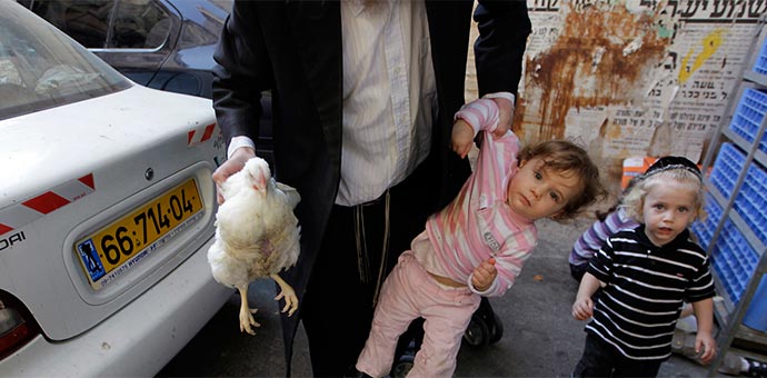 man holding chicken by wings with one hand, holding child by arm with the other hand